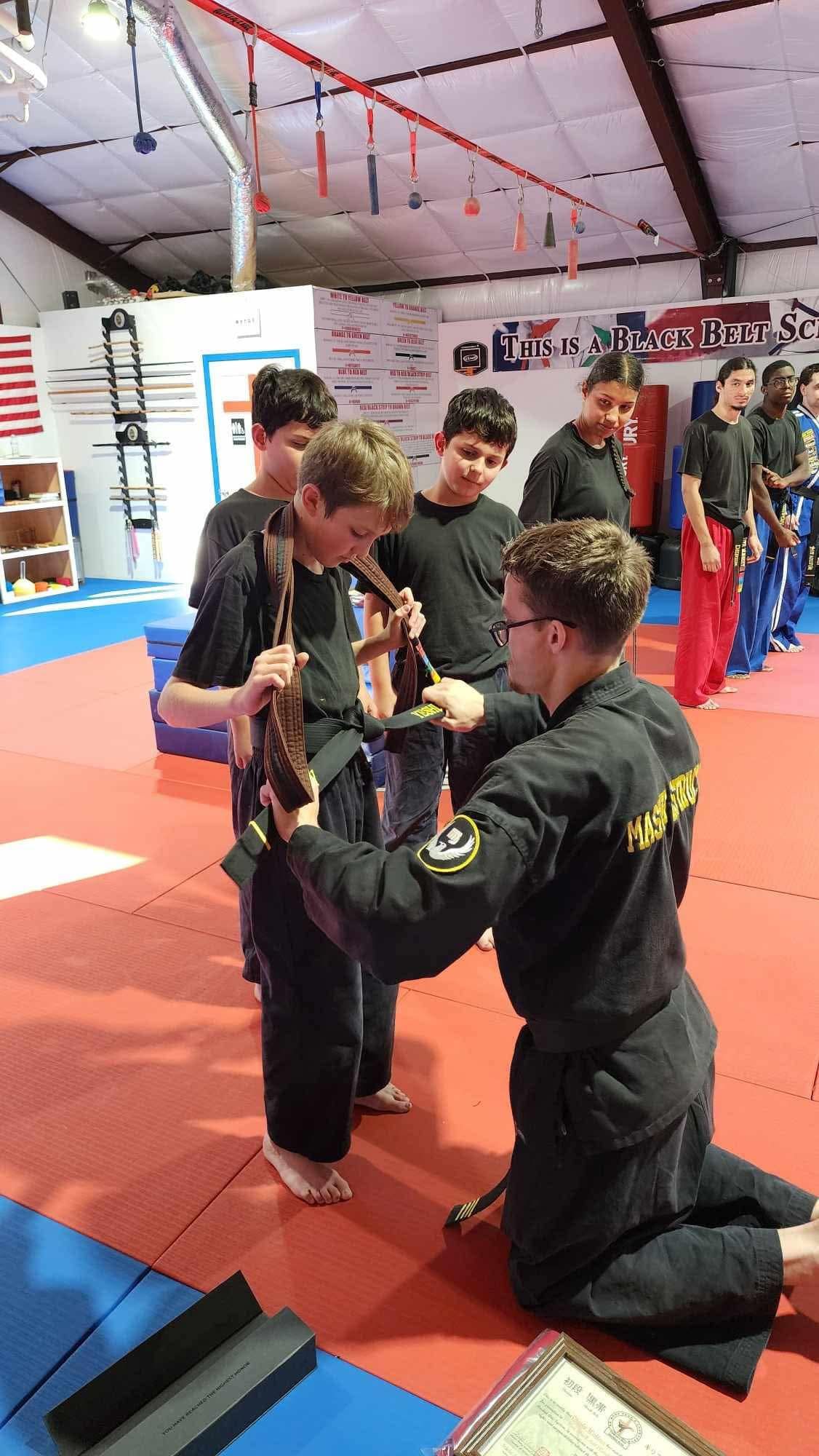 An instructor tying a newly earned belt on a student during a belt test