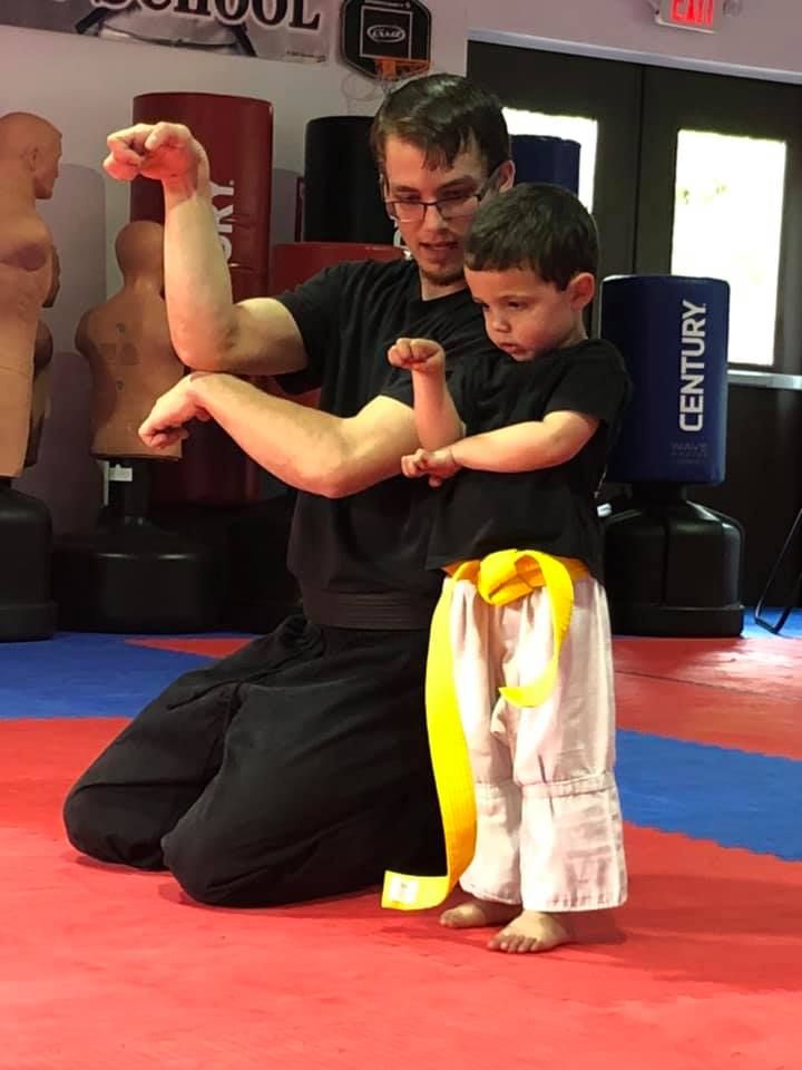 An instructor working one-on-one with a young yellow-belt student