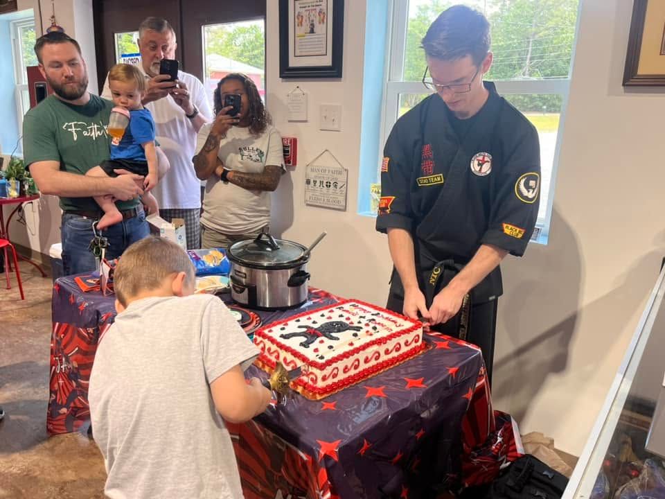 Birthday child cutting the cake with a real sword, guided by an instructor