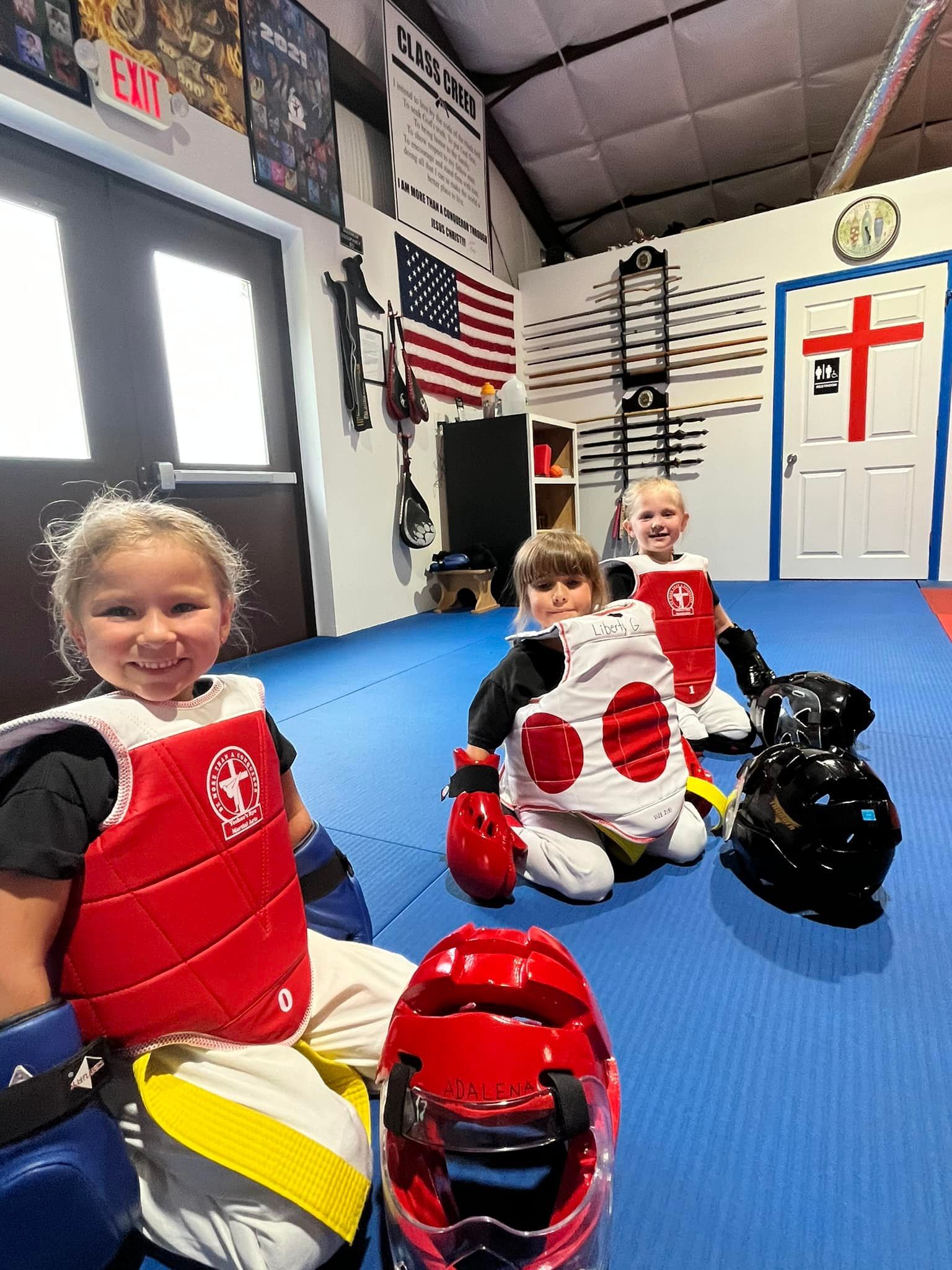 Smiling young students suited up in red sparring gear