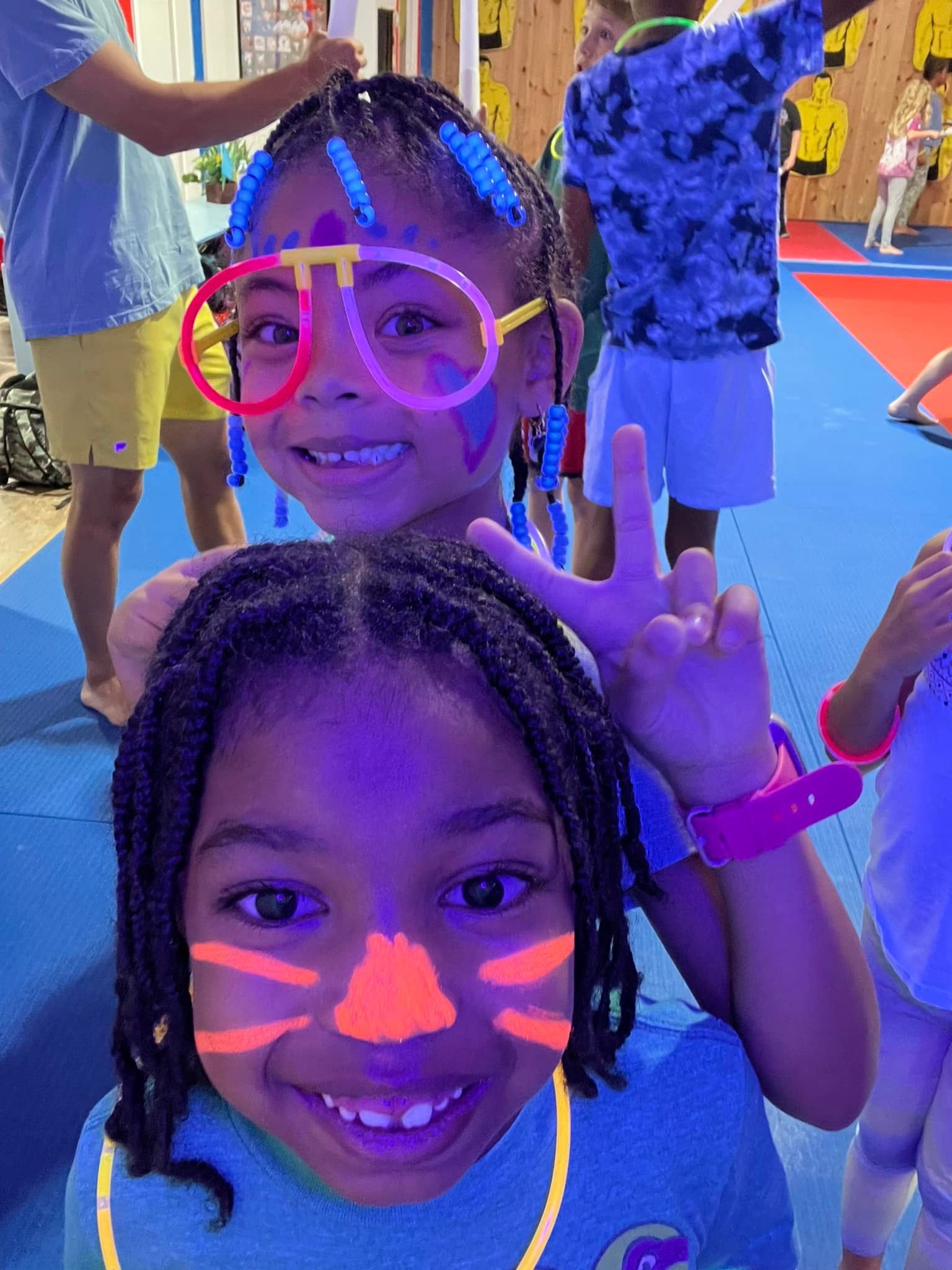 Kids with glow accessories and face paint at a Parents Night Out