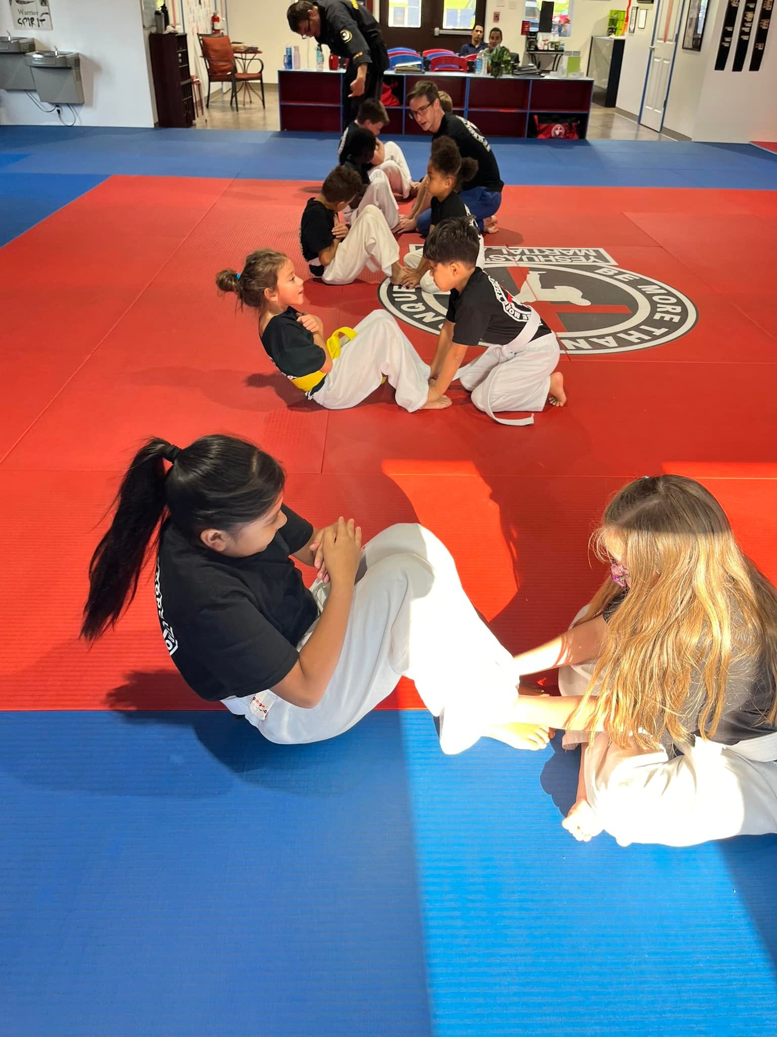 Two students practicing ground technique on the mat