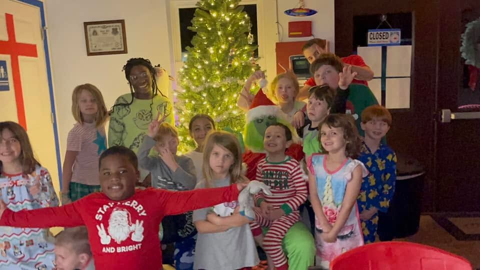 Kids in pajamas at a themed Parents Night Out around the Christmas tree