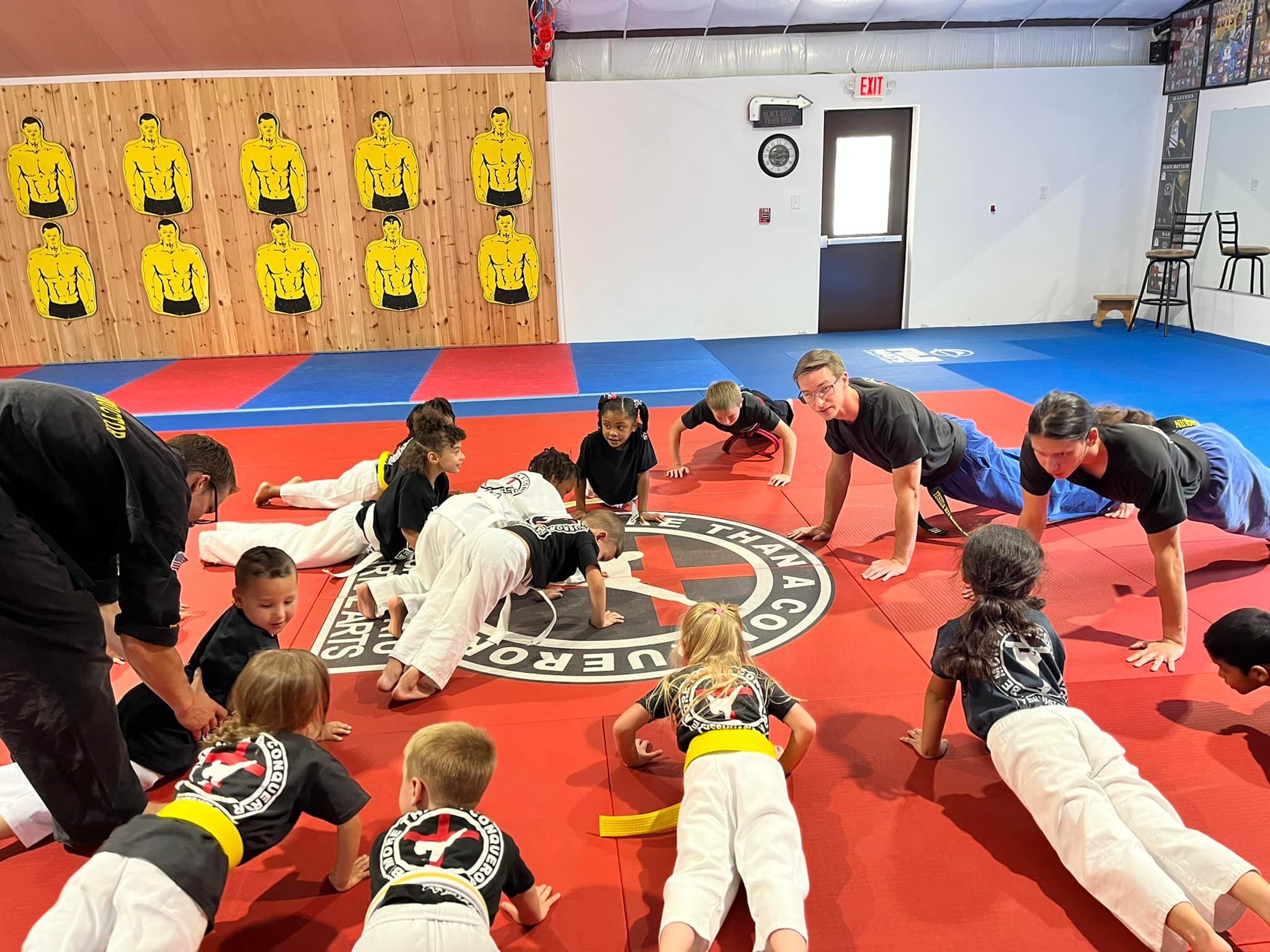 Young students stretching through warm-ups on the dojo mat